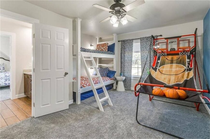 This bedroom is filled with a white bunk bed, basketball rings, and a traditional ceiling fan.