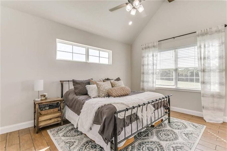 This bedroom has a high cathedral ceiling and a large window that overlooks an expansive view.