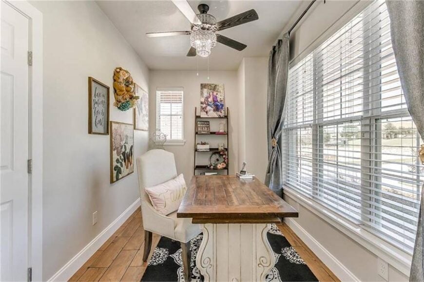 Study with a metal shelving unit and a wood plank desk paired with a beige cushioned chair.