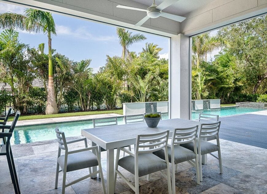 Outdoor dining with gray upholstered chairs and a rectangular dining table under the white ceiling fan.