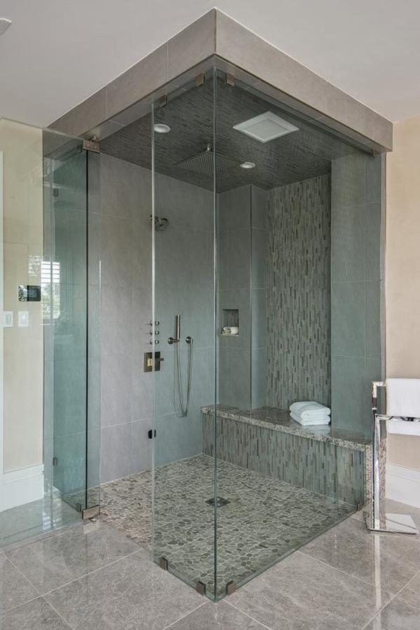 The walk-in shower is equipped with chrome fixtures and a tiled bench clad in linear mosaic.