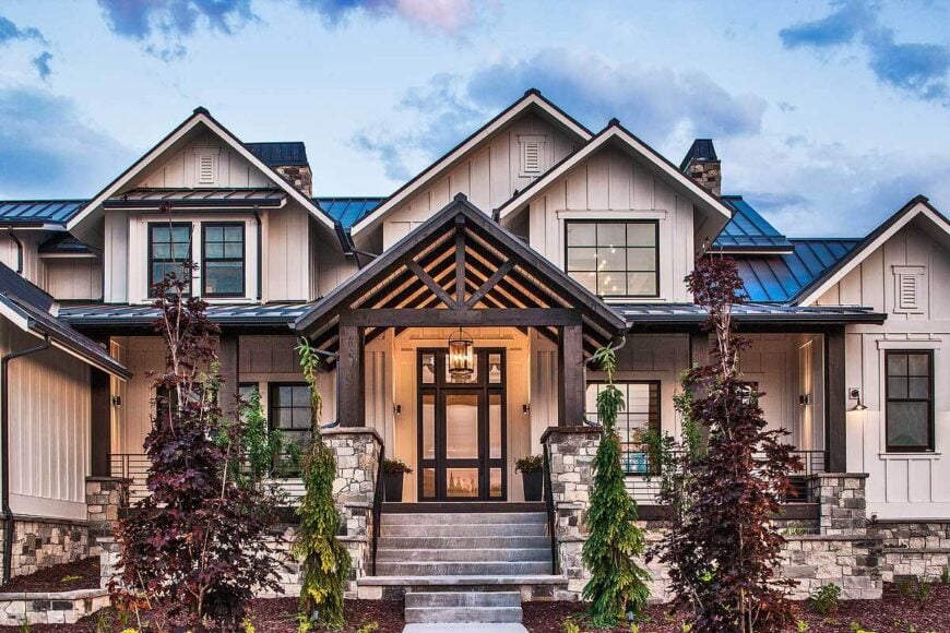 Home entry with a concrete stoop and a glass front door enclosed in a cathedral ceiling and stone columns.