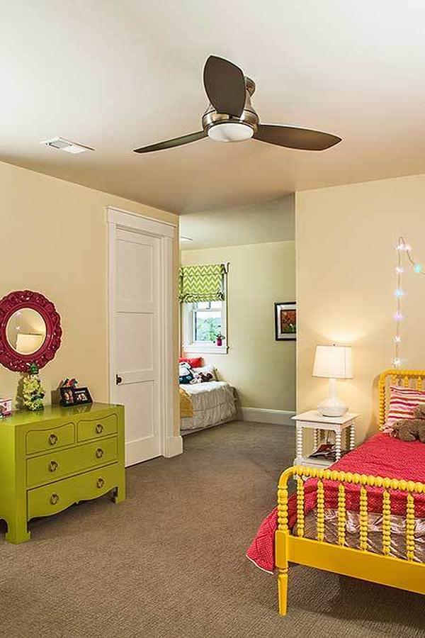 Another bedroom with carpet flooring, bold furniture, and light yellow walls adorned with fairy lights and red floral mirror.