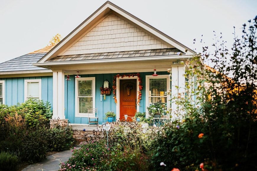 Home entry with a wooden front door and a covered porch lined with decorative pillars.