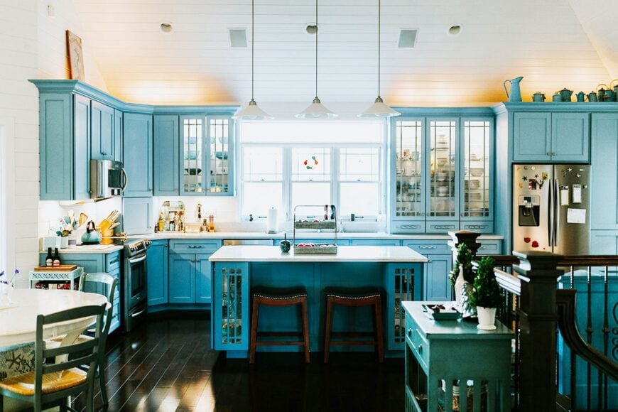 The kitchen offers blue cabinetry, stainless steel appliances, and a quartz top island paired with wooden stools.