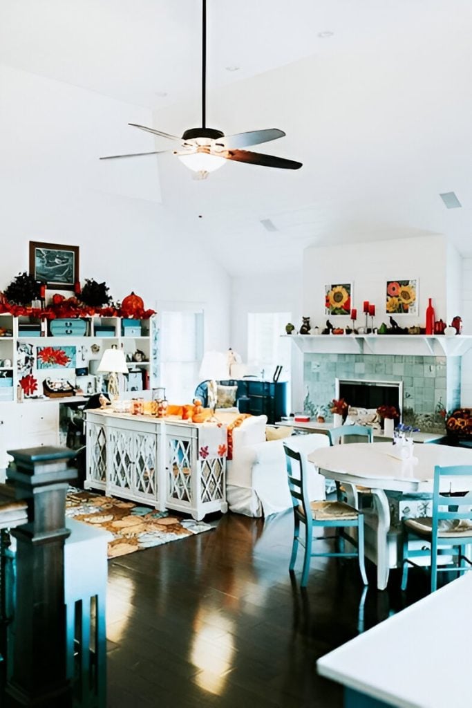 Shared dining and living room with a ceiling fan, round dining set, white built-ins, and a stylish mirrored cabinet sitting behind the sofa.