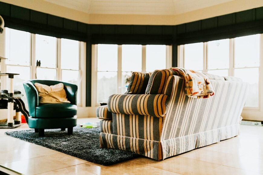 Sitting area with a stripe skirted sofa, a leather round chair, and massive windows that take in incredible views and ample lighting.