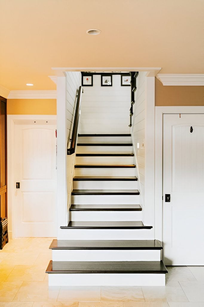 Traditional staircase composed of dark wood treads, white risers, and a black handrail.