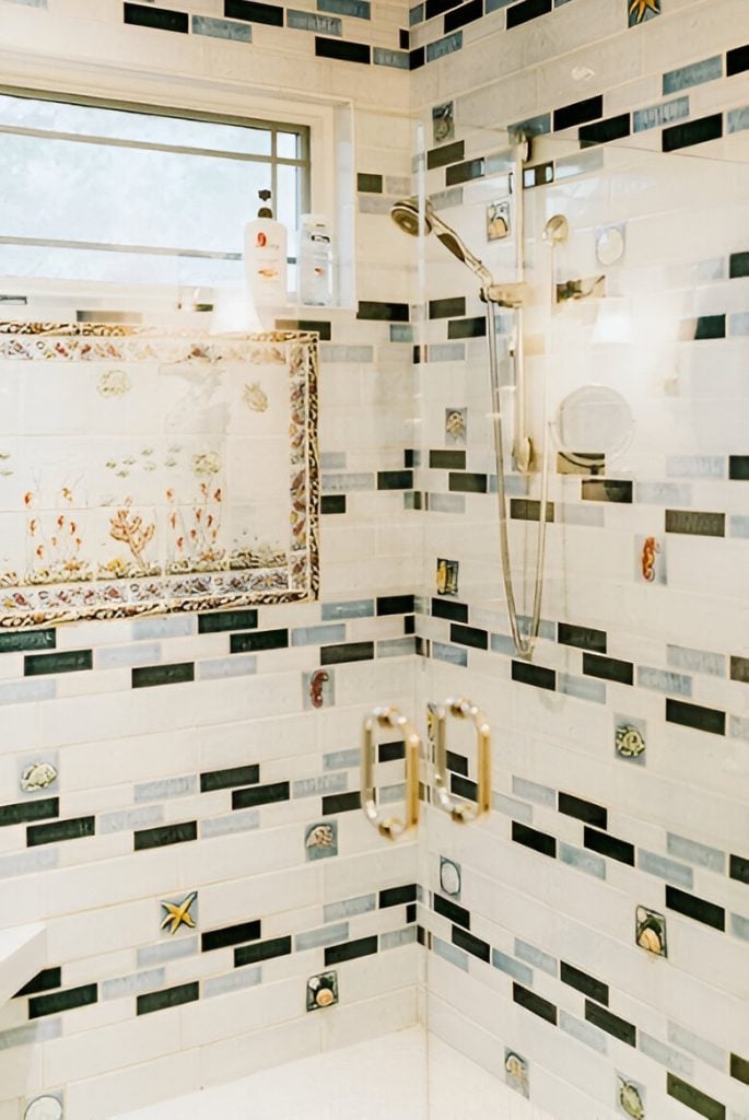 Captivating linear mosaic tiles highlight the walk-in shower with chrome fixtures.