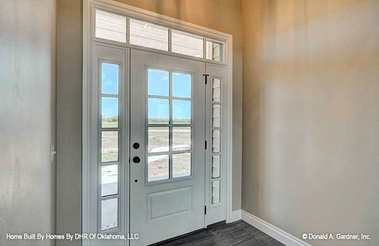 The foyer features a white glazed entry door surrounded with glass panels.