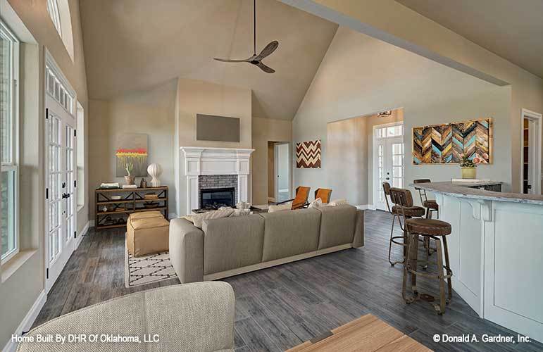 There's also a wooden shelving unit, stone fireplace, and a ceiling fan hanging from the high vaulted ceiling.