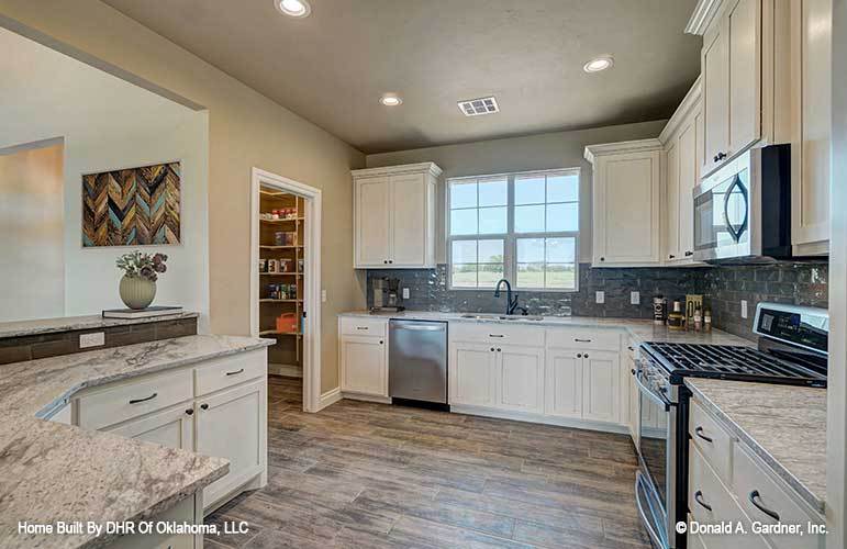 The kitchen is equipped with white cabinetry, stainless steel appliances, granite countertops, and a walk-in pantry.