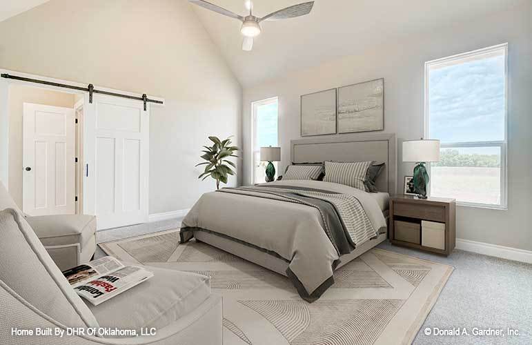 Primary bedroom with a cathedral ceiling, glazed windows, a white barn door, and gray carpet flooring topped with a textured area rug.