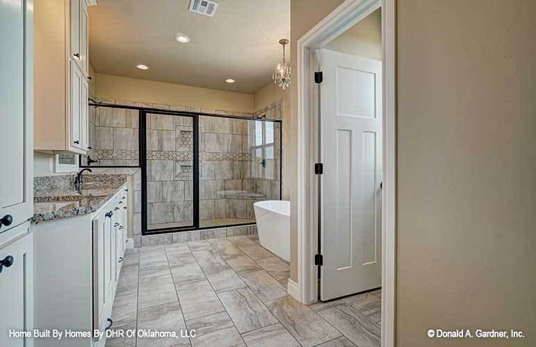 The primary bathroom offers a spacious walk-in shower, an immense vanity, and a freestanding tub illuminated by a crystal chandelier.