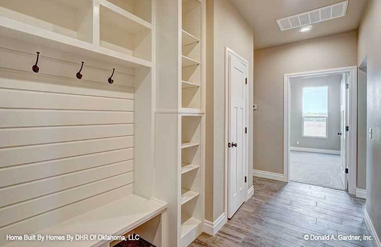 Mudroom with built-in bench and shelves along with coat hooks mounted against the white shiplap walls.