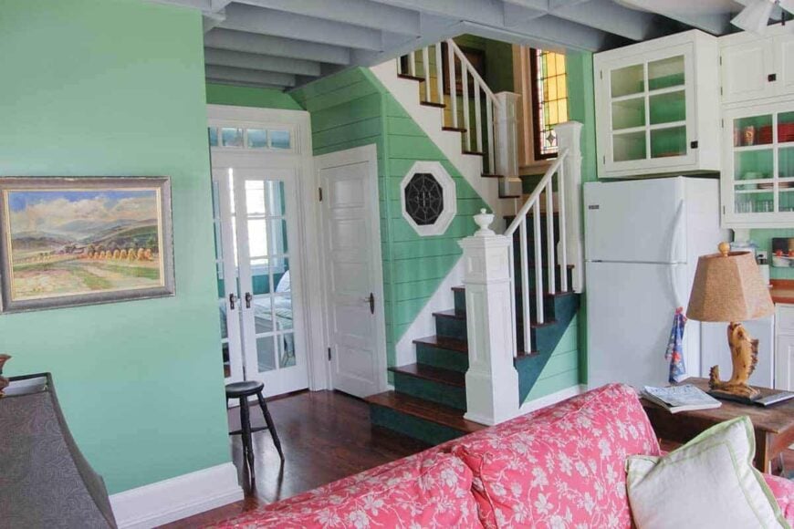 Behind the open living space are the staircase and a french door that opens to the primary bedroom.