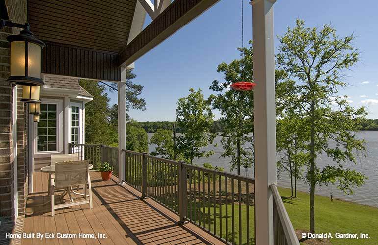 Back deck with round table and chairs, warm sconces, and a breathtaking lake view.