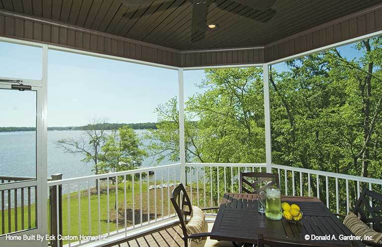Wood paneled ceiling, white railings, and a glass door house the screened porch.