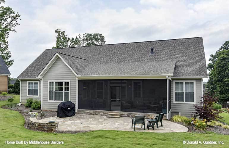 The rear view boasts a large screened porch and an open patio filled with built-in concrete bench and wooden chairs.