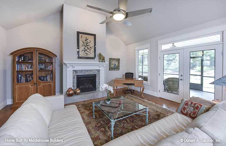 Living room with a large L-shaped sofa, glass top coffee table, a stone fireplace, and a french door that leads out to the screened porch.
