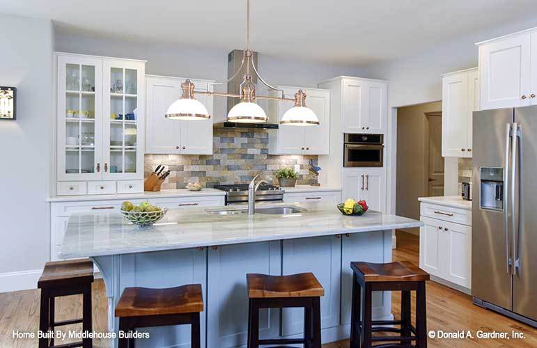 The kitchen is equipped with stainless steel appliances, white cabinetry, and a double bowl sink fitted on the breakfast island.