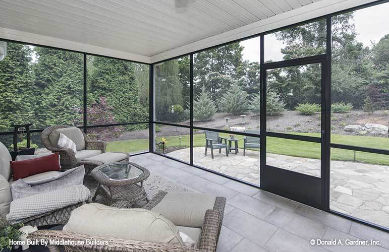 The screened porch offers cozy wicker seats overlooking the open patio and its serene surrounding.