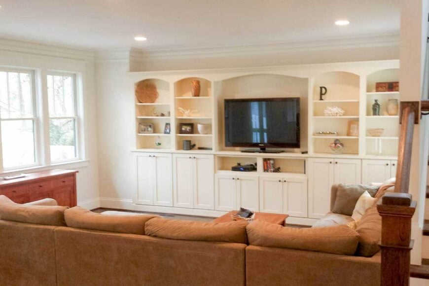 The living room offers a brown sectional sofa and a flatscreen TV flanked with built-in cabinets.