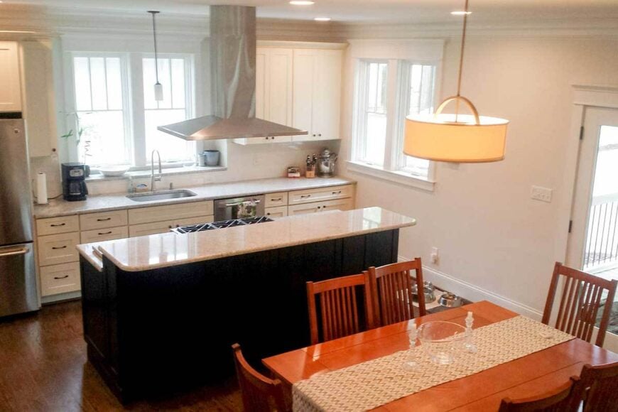 Eat-in kitchen with stainless steel appliances, white cabinets, and a two-tier island fitted with a cooktop.