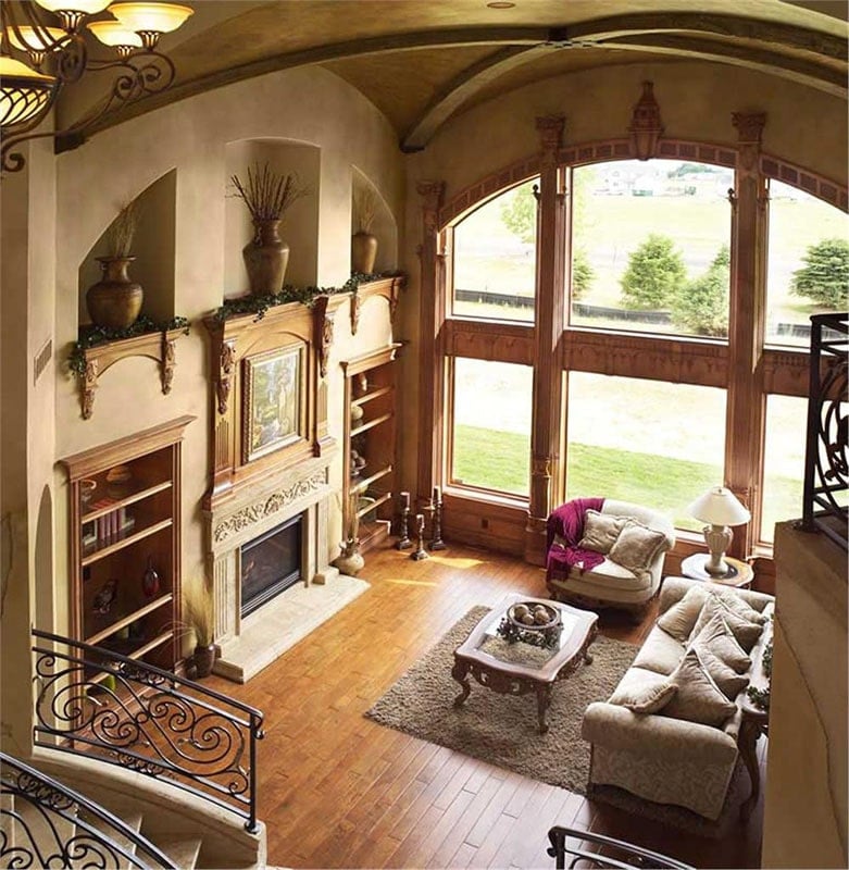Inset built-ins flanking the fireplace, classy beige seats, and a wooden coffee table over a shaggy area rug complete the living room.