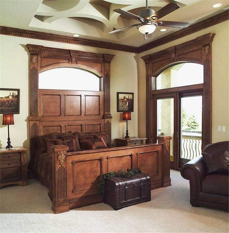 The primary bedroom offers a carved wooden bed, round armchair, and glass sliding doors with an arched transom window on top.