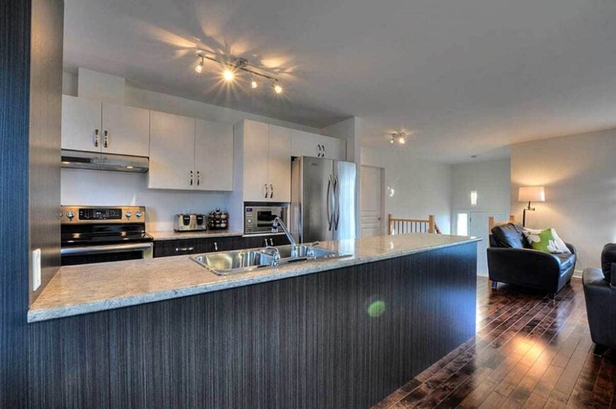 The kitchen is equipped with sleek cabinetry, stainless steel appliances, and a granite top peninsula fitted with an undermount sink.