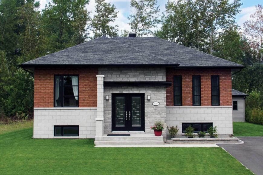 Home facade showcasing the brick exterior, hipped roofs, stone accents, and a french entry door.