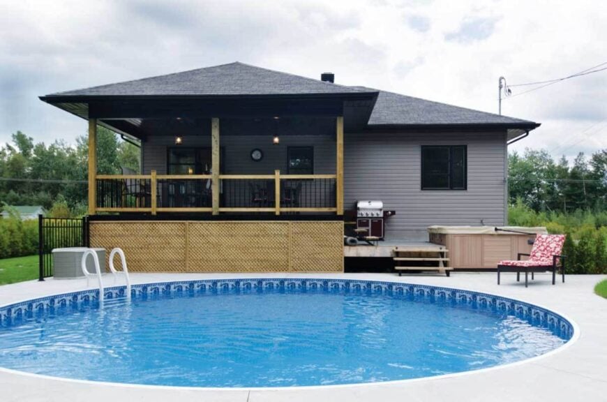 Another version of rear exterior showcasing a covered porch, deck with summer kitchen, and a round swimming pool.