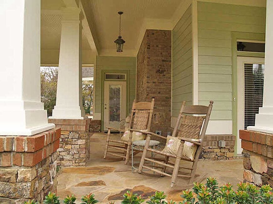 A closer look at the porch shows the round side table and wooden rocking chairs accented with floral pillows.