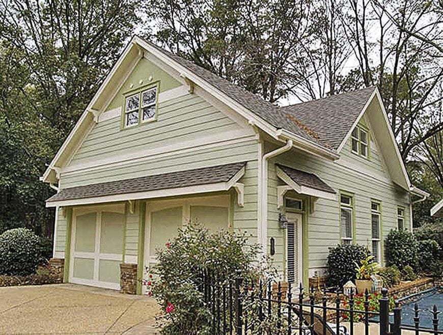Detached garage with mint green siding, gable rooflines, and shed roofs fixed above the wooden and glass doors.