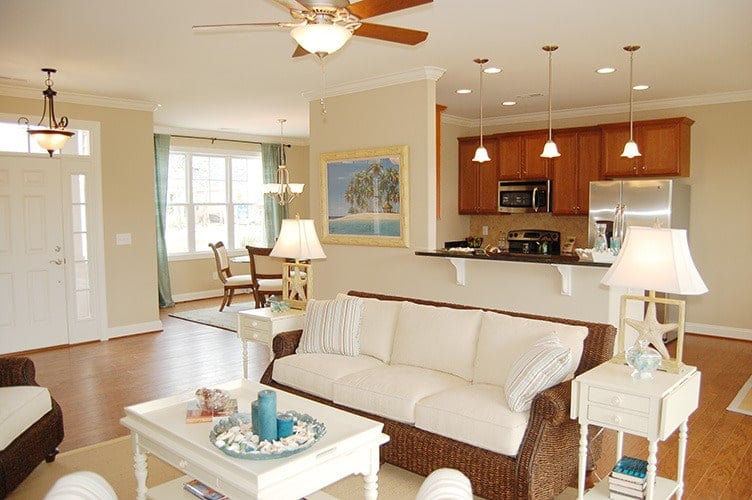 Sitting behind the living area is the kitchen with wooden cabinetry, stainless steel appliances, and ambient lighting.