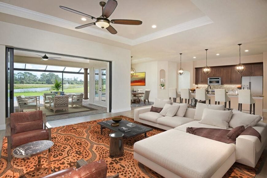 Living room with leather armchairs and an L-shaped sofa paired with a low coffee table. The sliding doors across open to the covered lanai.