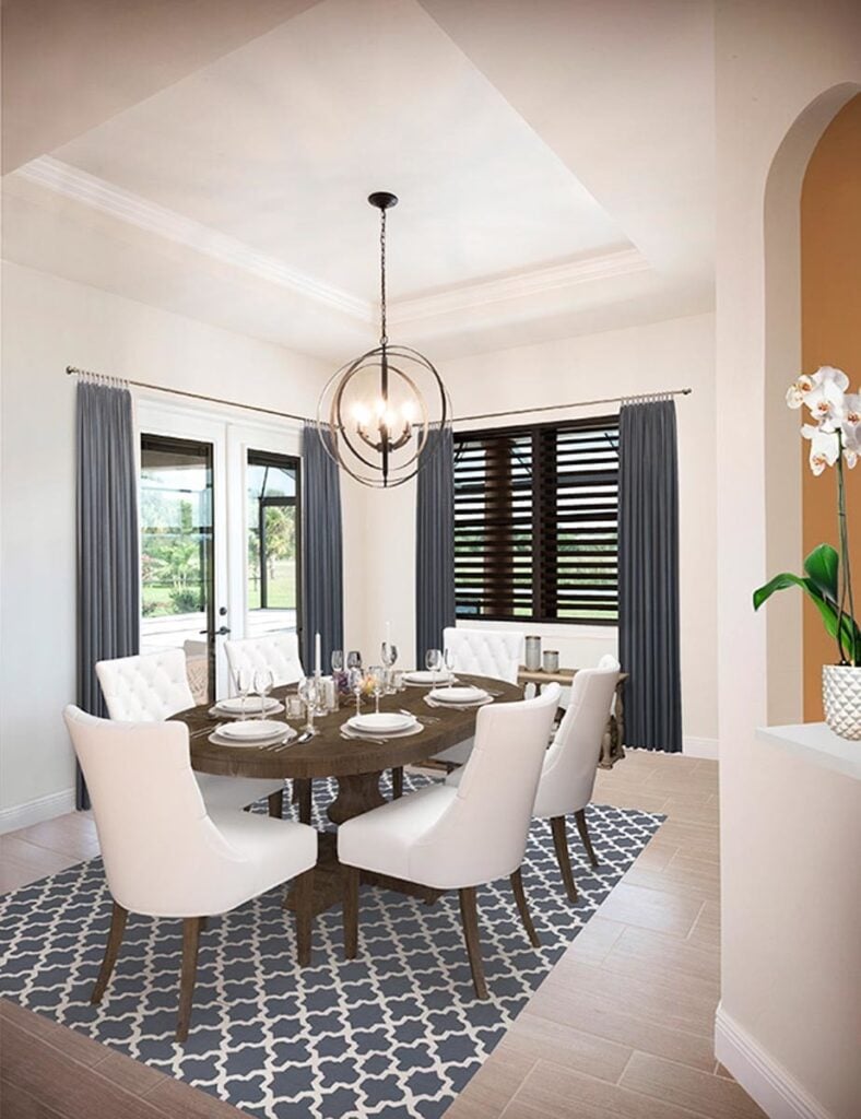 The formal dining room offers an oval dining table and white tufted chairs sitting on a blue patterned area rug.