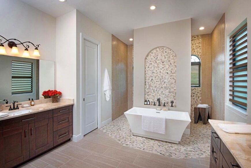 Primary bathroom with two vanities and a freestanding tub situated in front of the shower area.
