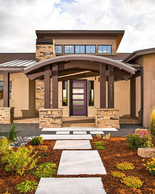 A concrete walkway leads to the covered front porch enclosed in a barrel roof and tapered columns.