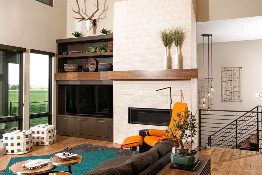 Living room with multi-colored seats, a modular coffee table, and a flatscreen TV situated next to the modern fireplace.