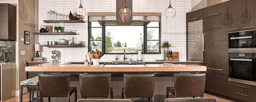 Kitchen with bespoke cabinets, black double wall oven, floating shelves, and a center island complemented with brown counter chairs.