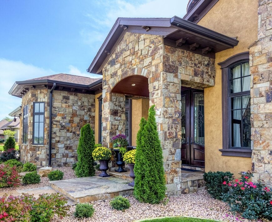 An angled side view of the home's entry showing the concrete steps leading to a stone archway.