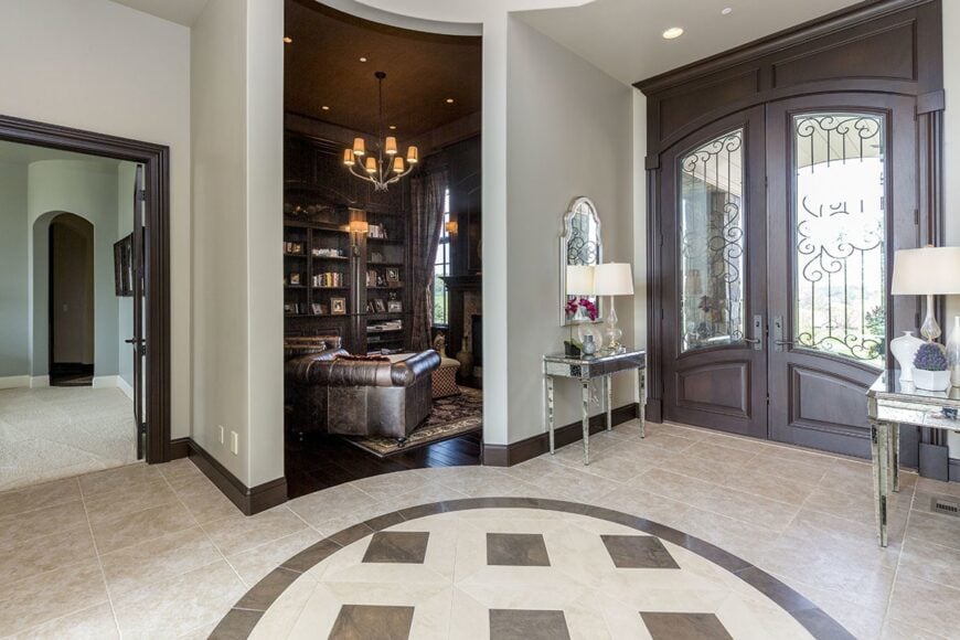 The foyer showcases mirrored console tables topped with sleek drum lampshades. It opens to a quiet den on the left.