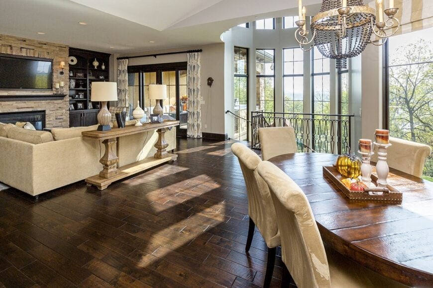 The breakfast area behind the hearth room offers beige velvet seats and an oval dining table lit by a classy candle chandelier.
