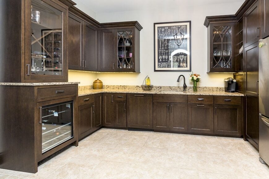 Spacious butlery with dark wood cabinets, elegant granite countertops, and a built-in beverage fridge.
