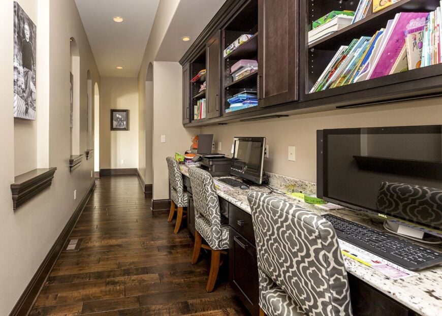 A long computer desk under the floating cabinet complemented with gray patterned chairs.