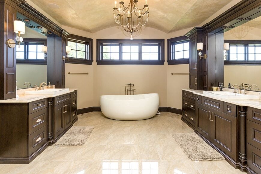 A farther view shows an equally large vanity and a beaded chandelier that hangs from the barrel-vaulted ceiling.