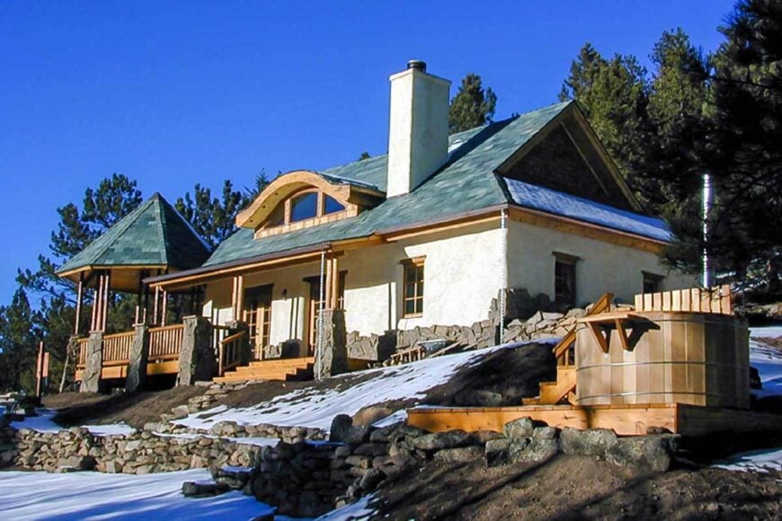 Angled front view showing the stucco exterior, stone concrete chimney, a curved dormer, and the gazebo.