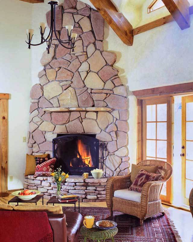 The living room offers wicker and leather chairs, metal coffee tables, and a kiva fireplace clad in striking stones.